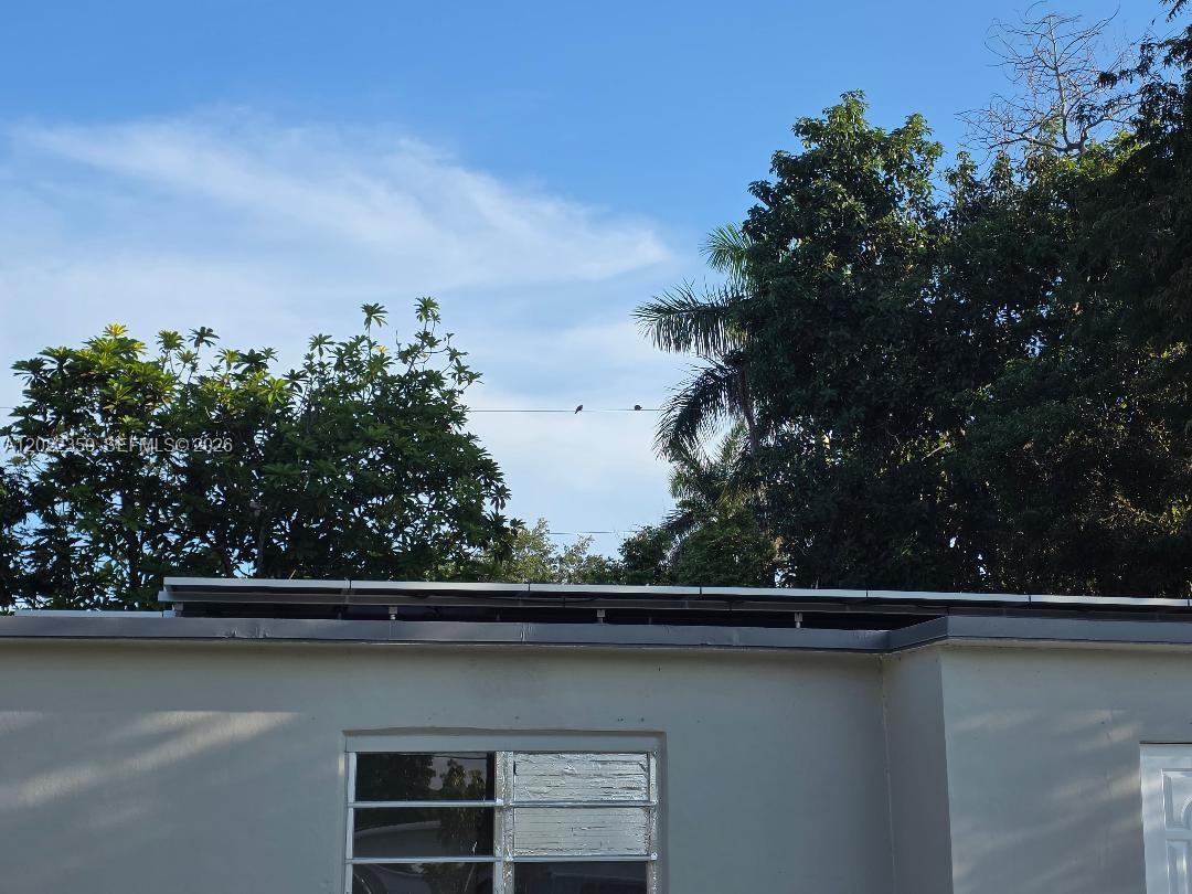 The exterior of a house features a flat roof with solar panels and a window — HOMESTEAD, FL
