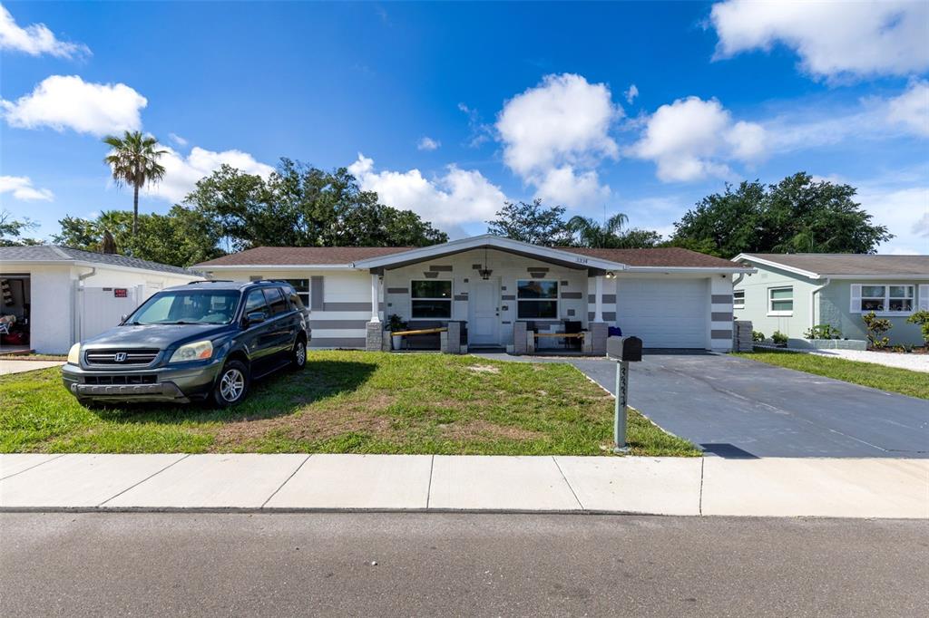 A single-story house with a gray exterior, a dark SUV, and a paved driveway — 3334 COLDWELL DRIVE, HOLIDAY, FL