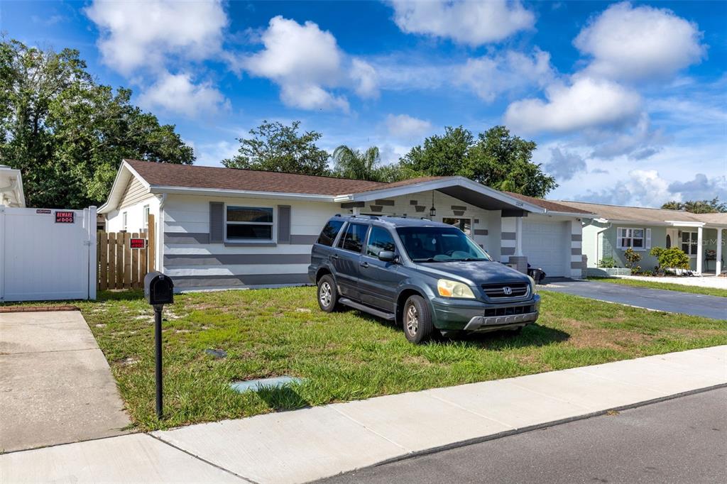 A single-story house with a gray and white exterior sits behind a parked SUV — 3334 COLDWELL DRIVE, HOLIDAY, FL