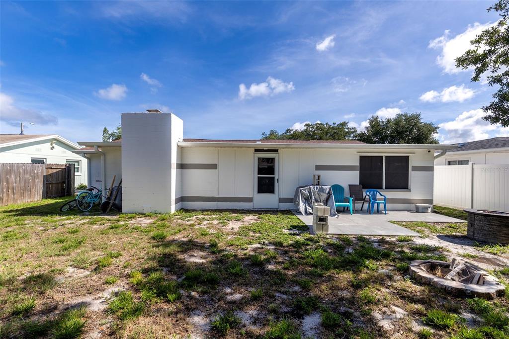 The exterior of a white house features a chimney, a patio, and a backyard — 3334 COLDWELL DRIVE, HOLIDAY, FL