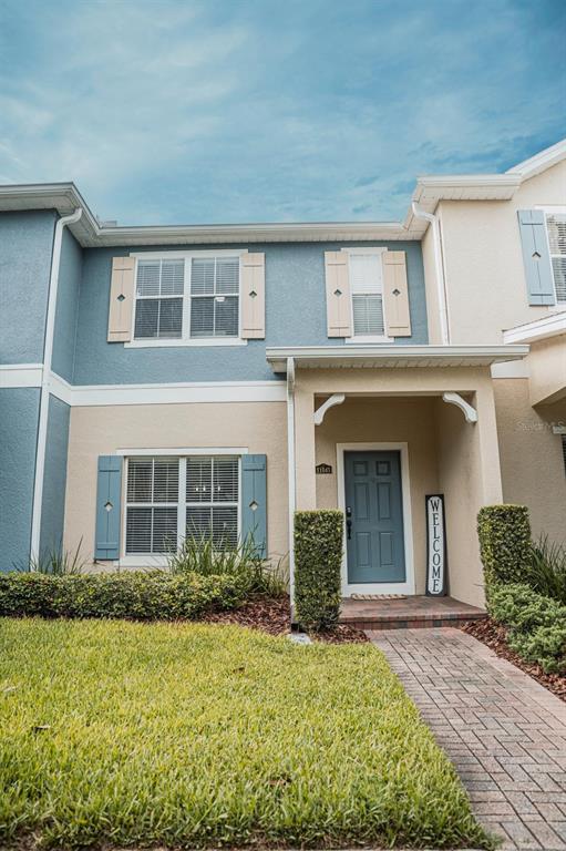 The exterior of a two-story townhouse features a blue door, shutters, and a brick walkway — 11843 DEER PATH WAY, ORLANDO, FL