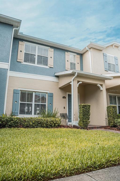 A two-story townhouse exterior features blue and beige stucco walls with blue shutters — 11843 DEER PATH WAY, ORLANDO, FL