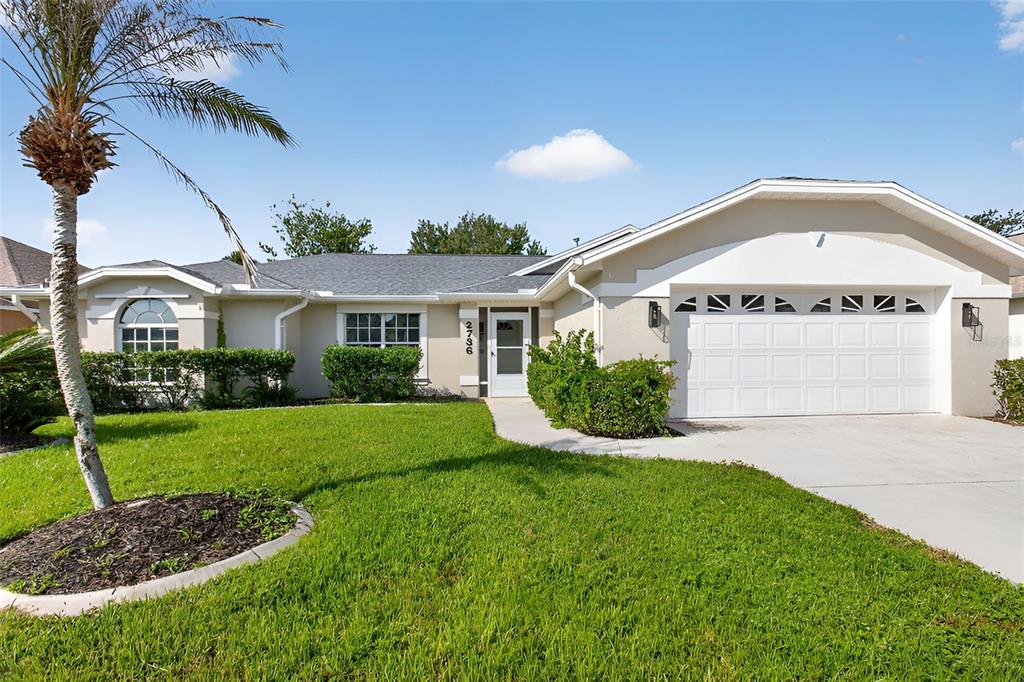 A single-story house with a white garage, a palm tree, and a green lawn — 2736 TURNBULL ESTATES DRIVE, NEW SMYRNA BEACH, FL