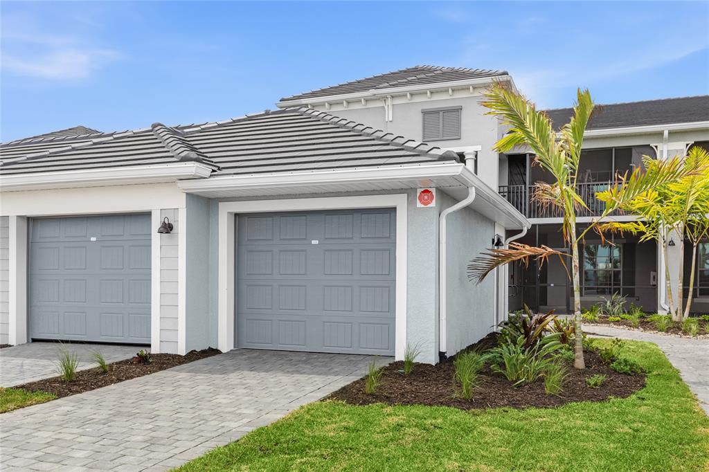 A two-car garage with gray doors and a paved driveway in front of a building — 19007 SCALLOP LOOP UNIT 204, LAKEWOOD RANCH, FL