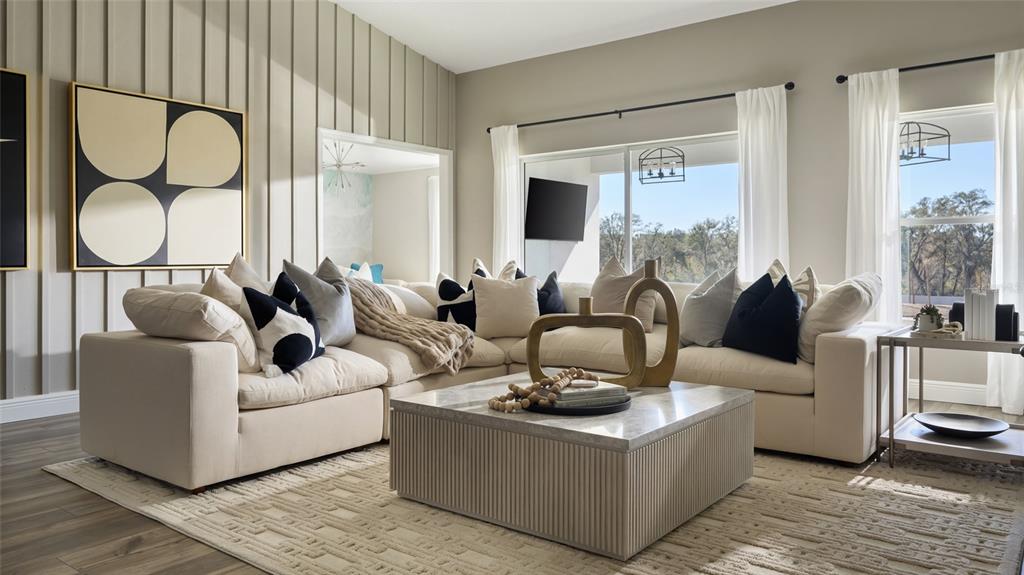 A living room features a large beige sectional sofa, a coffee table, and vertical wall paneling — 9836 ANNUNCIATION DRIVE, WESLEY CHAPEL, FL