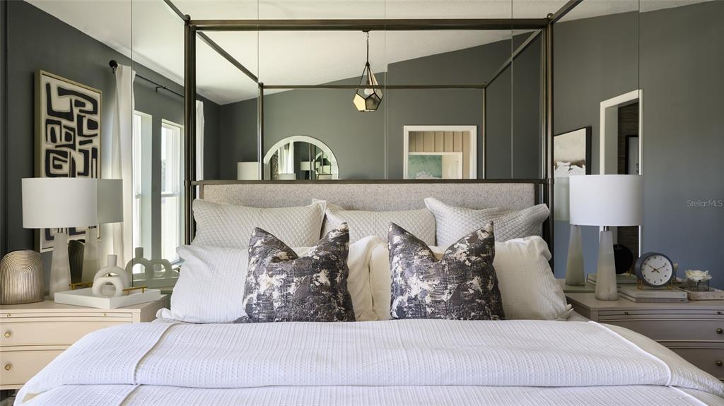 A bedroom features a canopy bed, mirrored wall panels, and gray walls with two nightstands — 9836 ANNUNCIATION DRIVE, WESLEY CHAPEL, FL