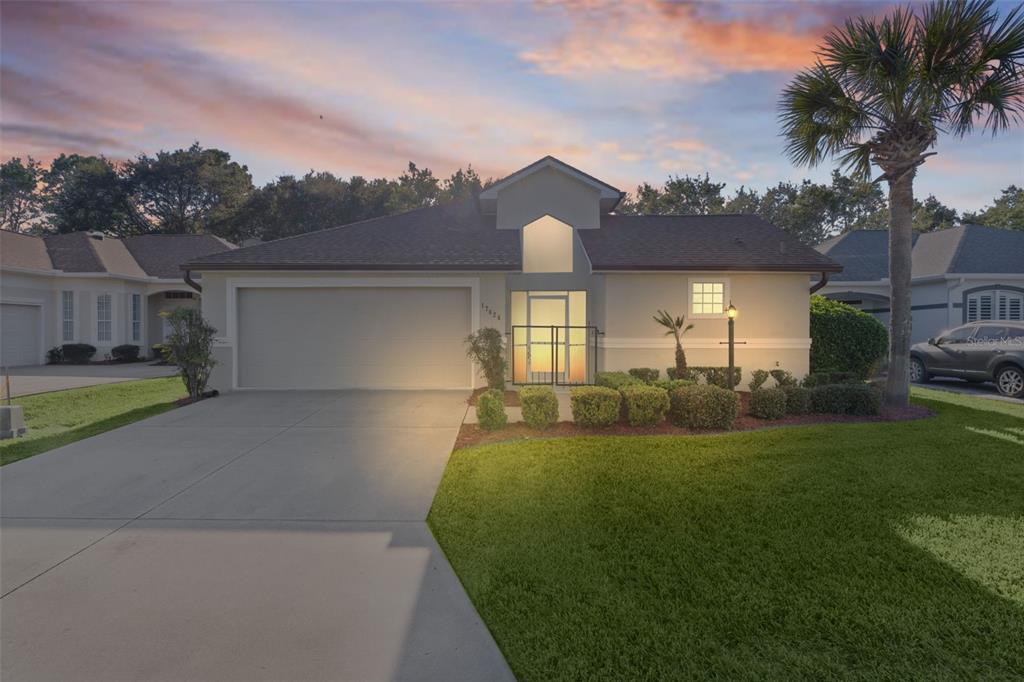 A single-story house with a two-car garage, a front lawn, and a palm tree — 17824 SE 113TH TERRACE, SUMMERFIELD, FL