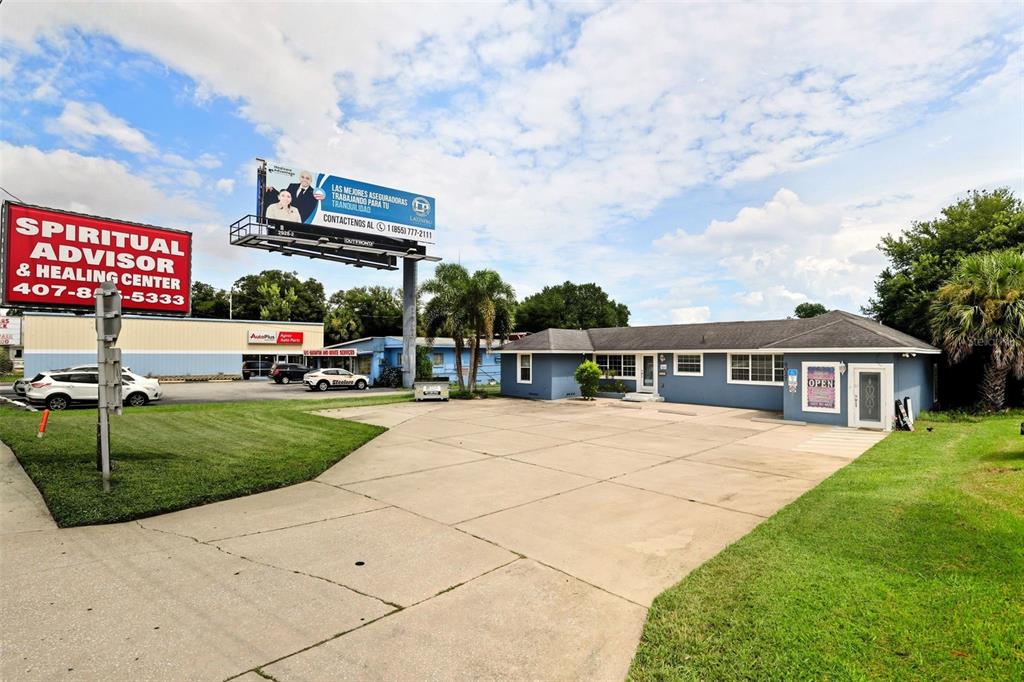 A blue commercial building with a concrete parking lot and a large billboard nearby — 8027 S ORANGE AVENUE, ORLANDO, FL
