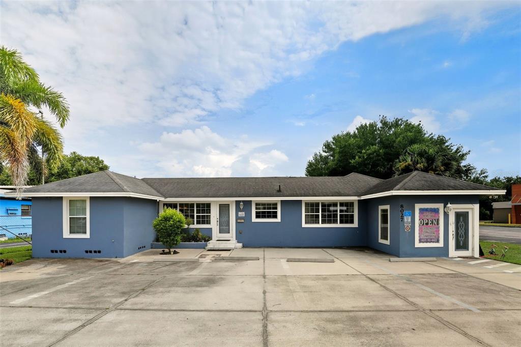 A single-story blue commercial building with a concrete parking lot in front — 8027 S ORANGE AVENUE, ORLANDO, FL
