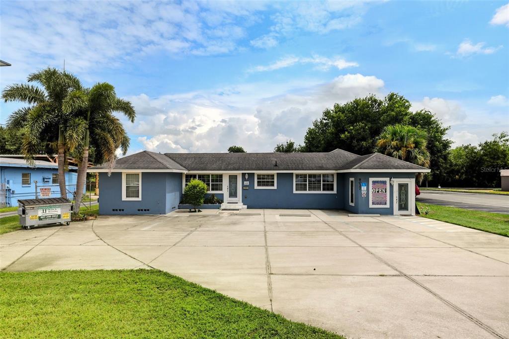 A single-story blue commercial building with a concrete parking lot and palm trees — 8027 S ORANGE AVENUE, ORLANDO, FL