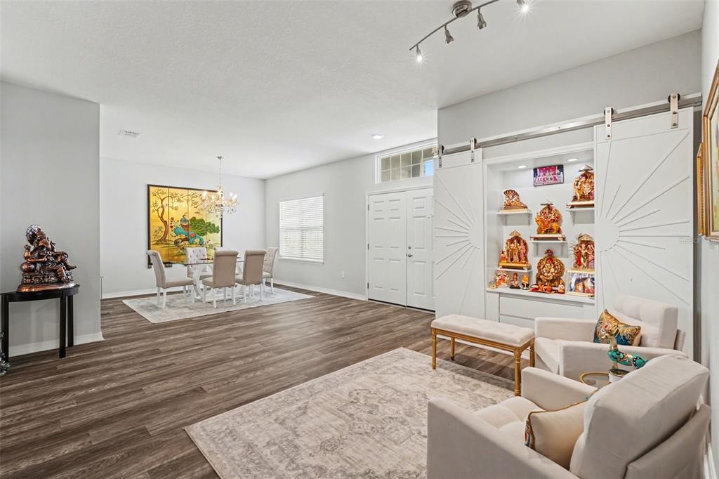 A living and dining area features wood-look flooring, a built-in display cabinet, and neutral furniture — 6749 ABBYWOOD LANE, ZEPHYRHILLS, FL