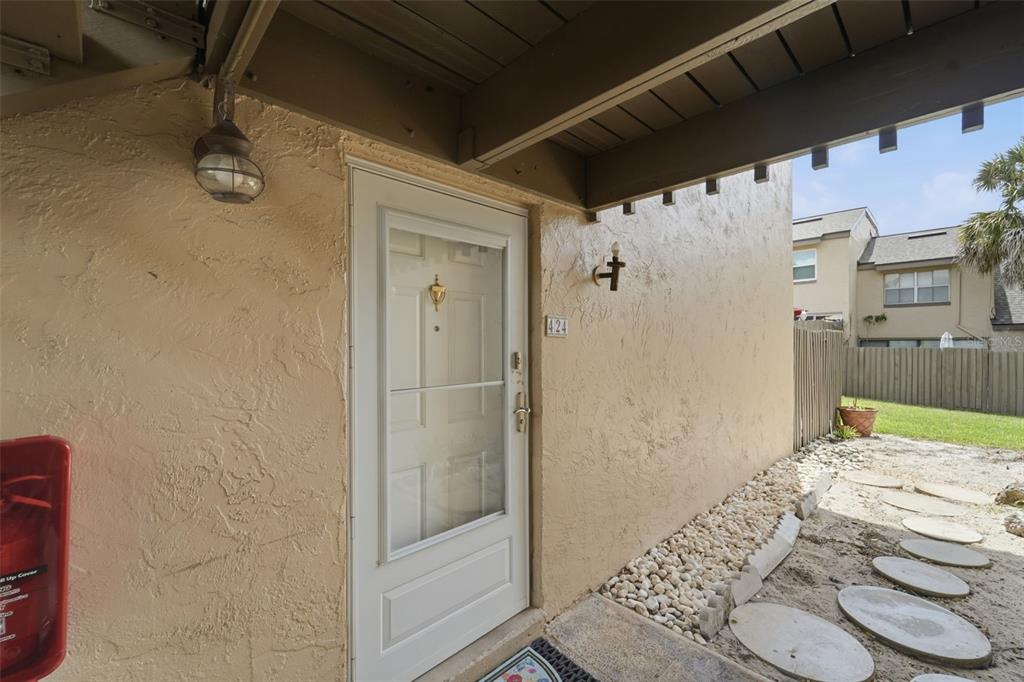 The exterior entrance of a residential unit features a white door, a light fixture, and stepping stones — 424 WINDMEADOWS STREET UNIT 424, ALTAMONTE SPRINGS, FL
