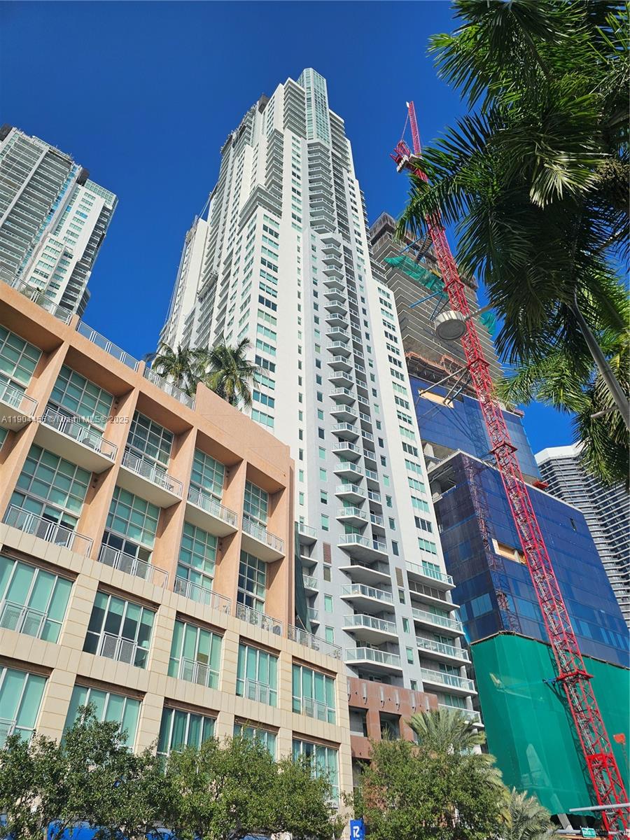 A low-angle view shows a tall white residential skyscraper next to a shorter tan building — 244 Biscayne Blvd # 308, Miami FL 33132, MIAMI, FL