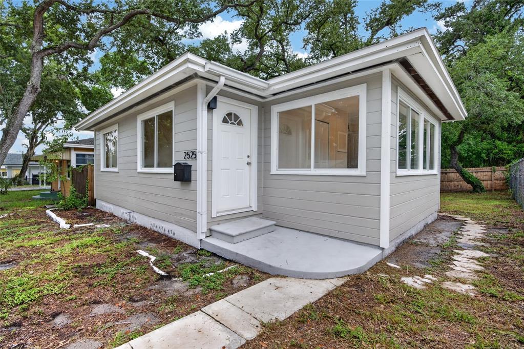 A small, light gray, single-story house with a white door and a concrete front stoop — 2525 21ST STREET S, ST PETERSBURG, FL