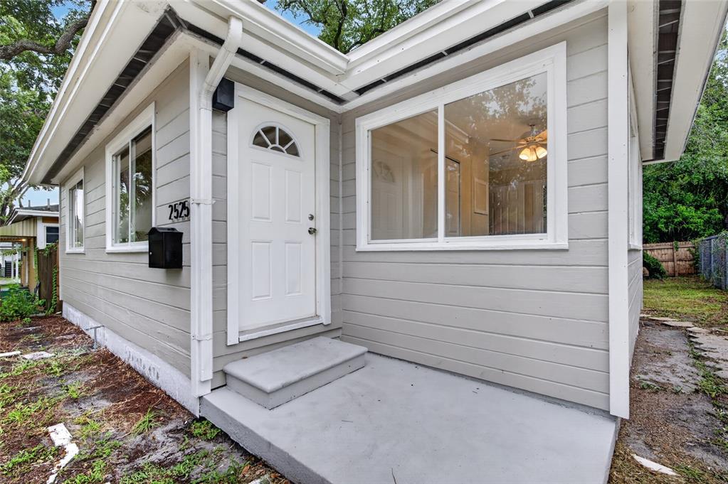 The exterior of a light gray house features a white front door and concrete porch — 2525 21ST STREET S, ST PETERSBURG, FL