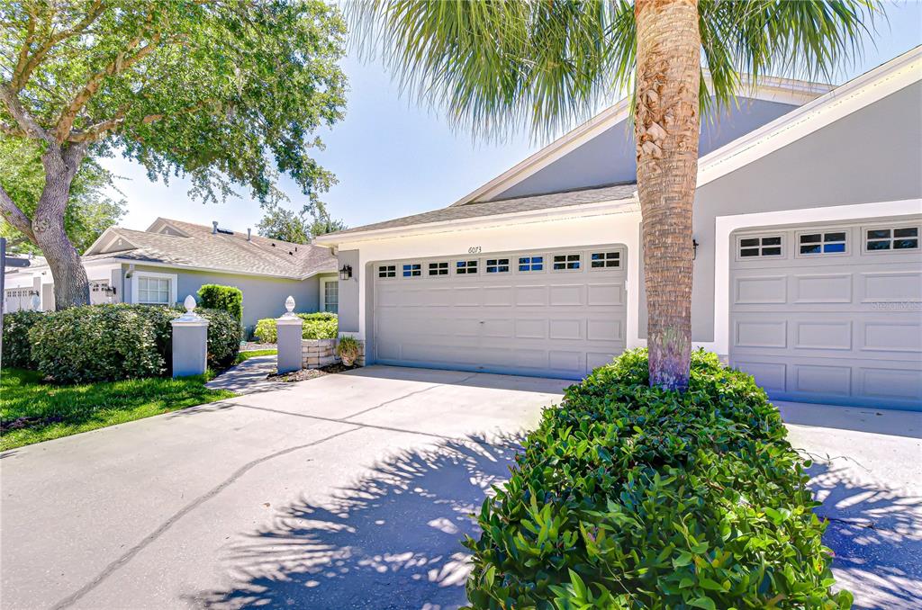 A view of a house exterior featuring two garage doors, a driveway, and landscaping — 6073 SANDHILL RIDGE DRIVE, LITHIA, FL