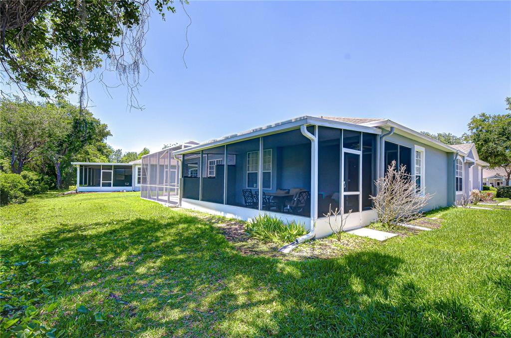 A view of a house exterior featuring a large screened-in porch and a grassy yard — 6073 SANDHILL RIDGE DRIVE, LITHIA, FL