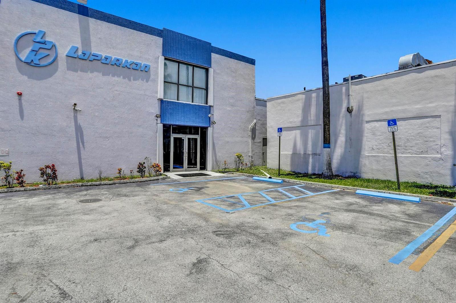 An exterior view of a commercial building with a blue logo and handicap parking spaces — 3775 NW 77th Street, Miami FL 33147, MIAMI, FL