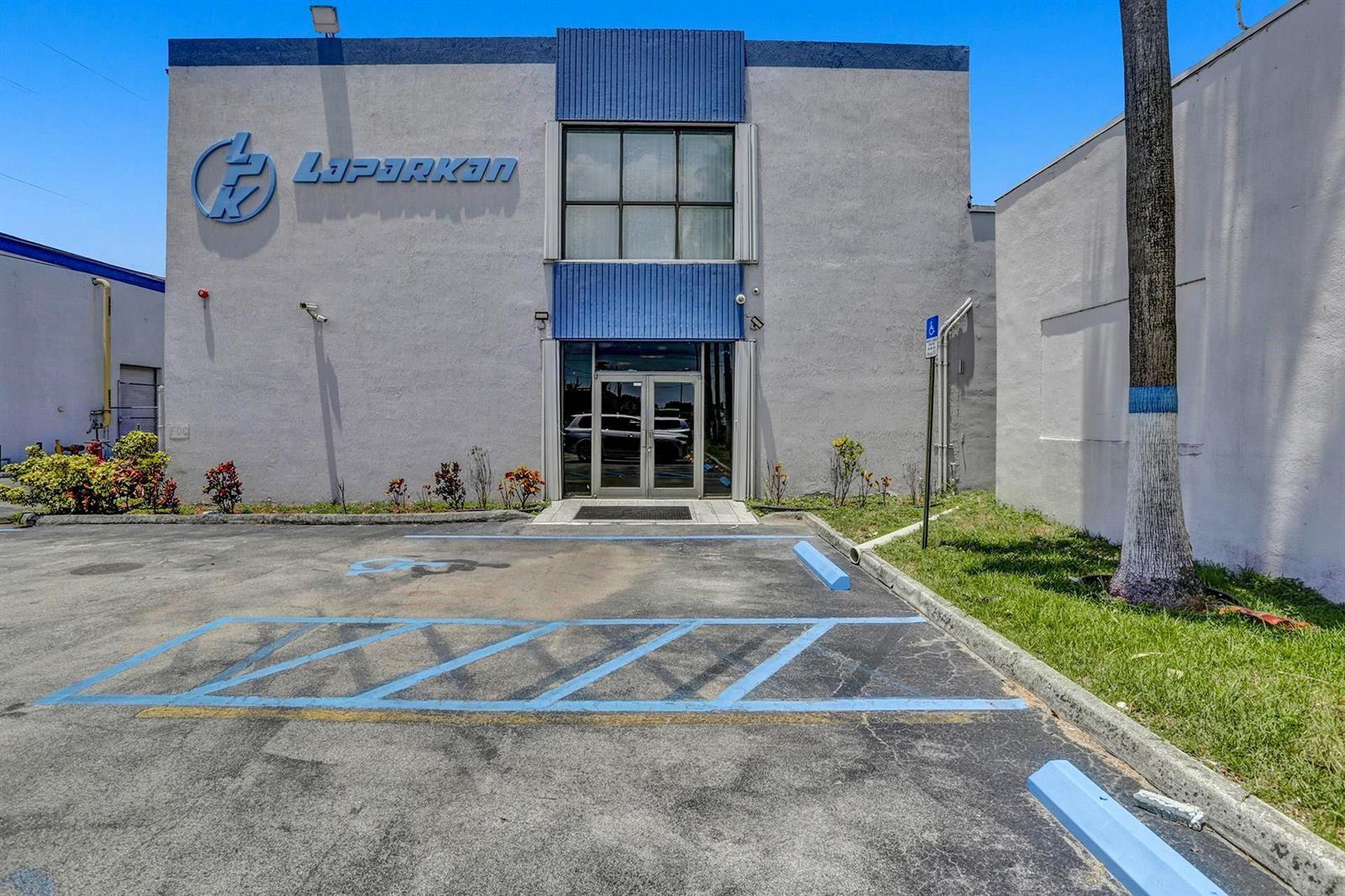 The exterior of a commercial building features a blue logo, a glass entrance, and a handicap parking space — 3775 NW 77th Street, Miami FL 33147, MIAMI, FL