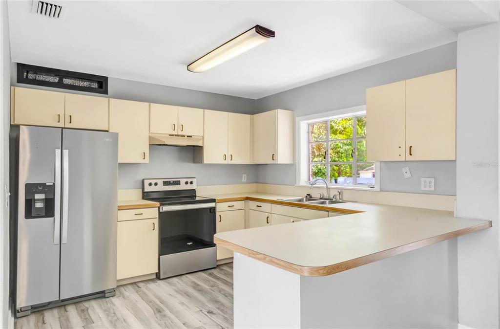 A kitchen with light-colored cabinets, stainless steel appliances, a peninsula, and wood-look flooring — 322 N FRANKFORT AVENUE, DELAND, FL