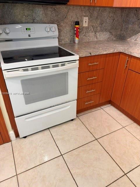 A kitchen features wood cabinets, granite countertops, tile flooring, and white appliances — 1501 NE 191st St # C107, Miami FL 33179, MIAMI, FL