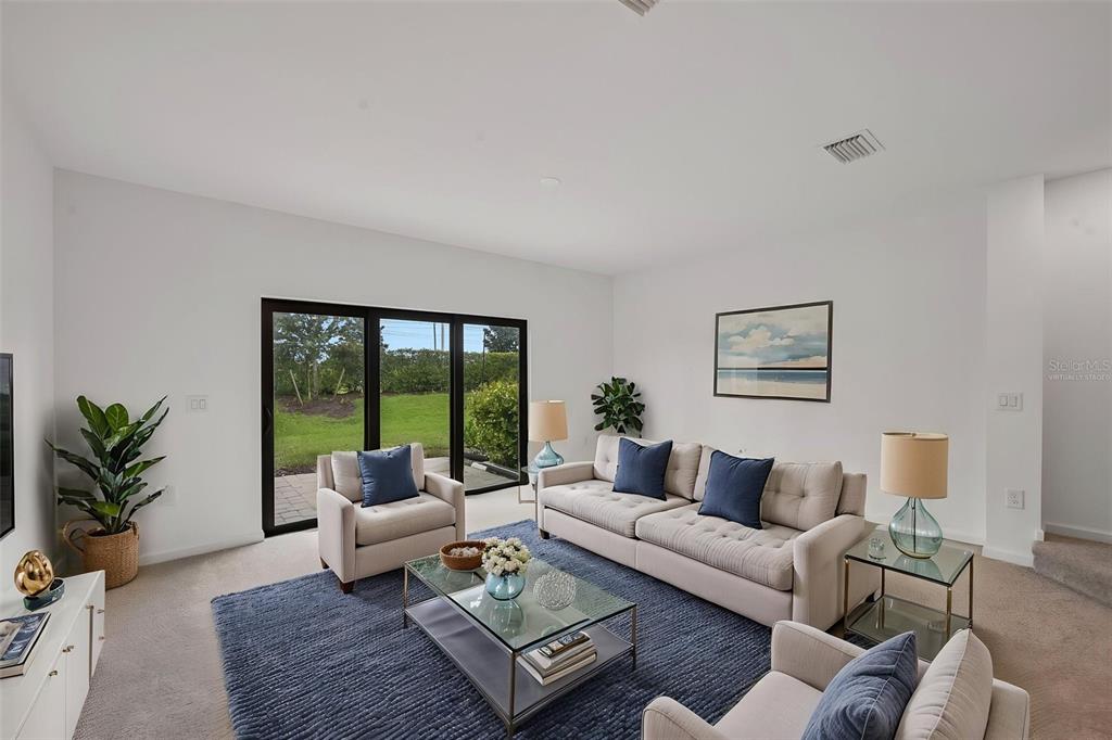 A living room features a beige sofa, two armchairs, a glass coffee table, and sliding doors — 6391 WATERSTONE PLACE, SARASOTA, FL