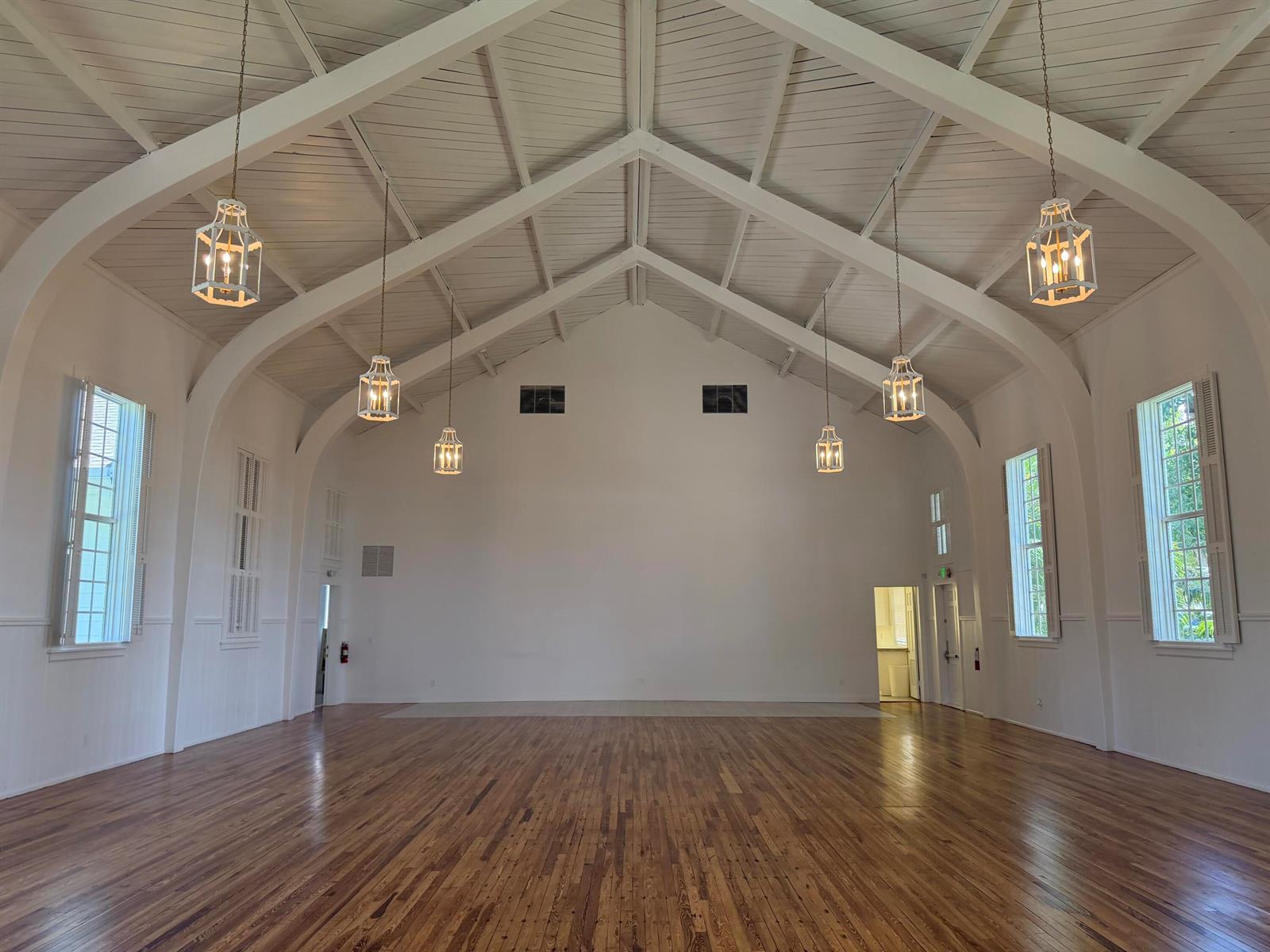 A spacious, empty hall features a vaulted ceiling, white walls, hardwood floors, and hanging lanterns — 200 SE 7th Avenue, Delray Beach FL 33483, DELRAY BEACH, FL