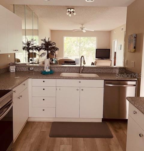 A kitchen with white cabinets, granite countertops, and a stainless steel dishwasher overlooks a living area — 8750 OLDE HICKORY AVENUE UNIT 9204, SARASOTA, FL