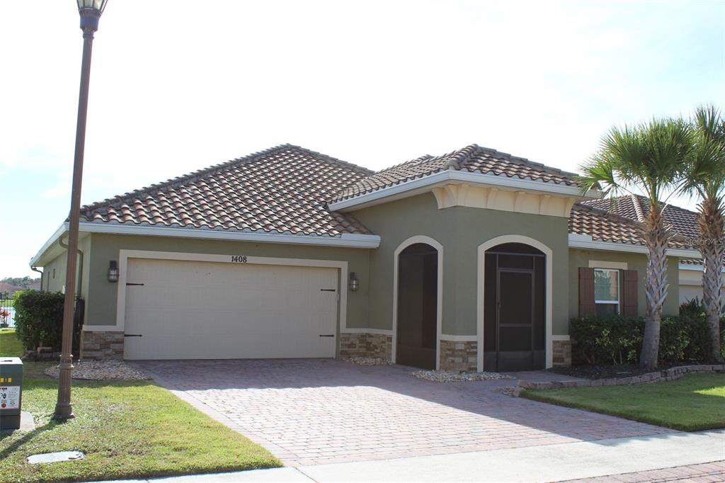 A one-story house with a tiled roof, beige stucco walls, and a two-car garage — 1408 LANIER POINT PLACE, KISSIMMEE, FL
