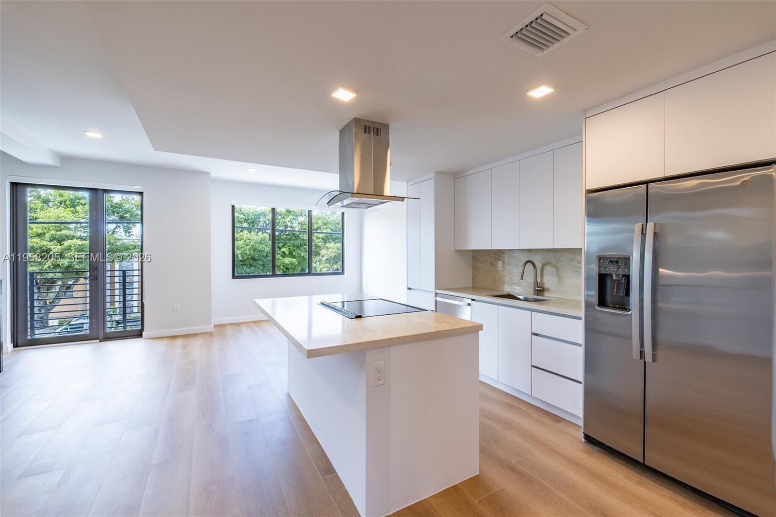 A modern kitchen features white cabinetry, a center island with a cooktop, and stainless appliances — 1376 SW 4th St # 401, Miami FL 33135, MIAMI, FL