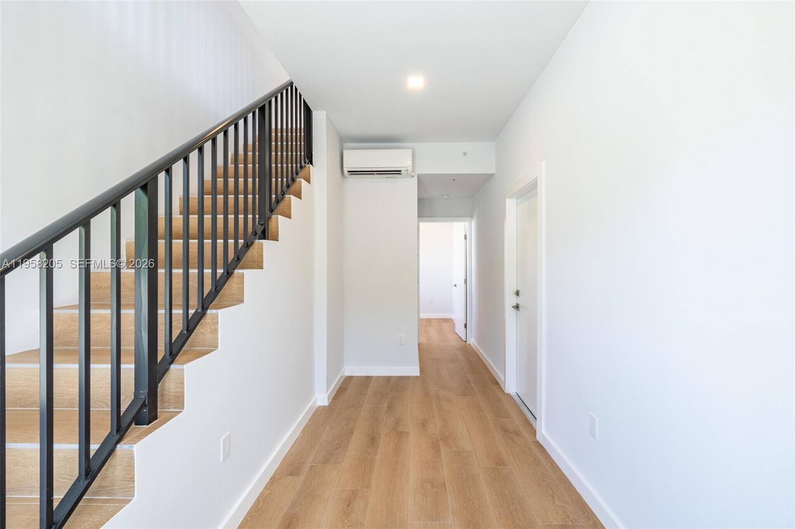 A hallway features light wood flooring, a staircase with a black railing, and white walls — 1376 SW 4th St # 401, Miami FL 33135, MIAMI, FL