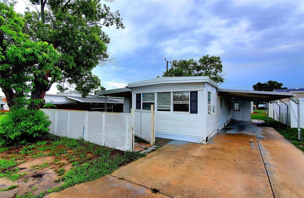 A single-story mobile home with white siding, a carport, and a white lattice fence — 1908 SHADY COVE DRIVE, HOLIDAY, FL