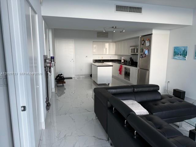 A modern open-concept kitchen with white cabinetry and a black leather sectional sofa — 92 SW 3rd St # 2109, Miami FL 33130, MIAMI, FL