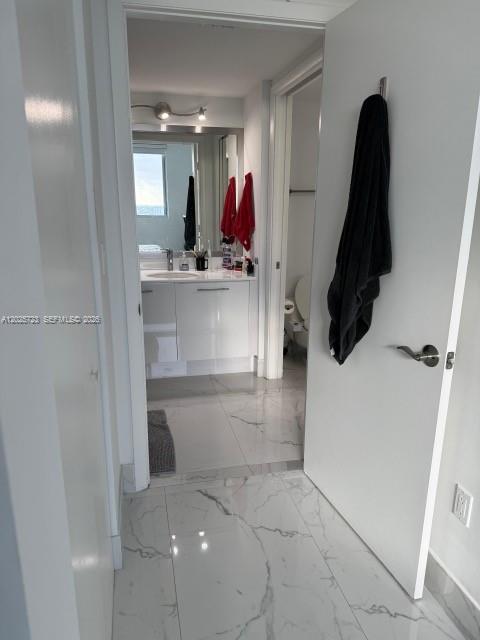 A view through a doorway into a modern bathroom with white cabinets and marble flooring — 92 SW 3rd St # 2109, Miami FL 33130, MIAMI, FL