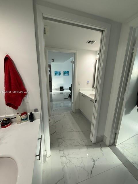 A bathroom with white marble-style flooring leads into an adjacent room through an open doorway — 92 SW 3rd St # 2109, Miami FL 33130, MIAMI, FL