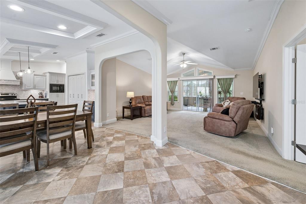 An open-concept living room and dining area featuring tile flooring, carpet, and vaulted ceilings — 8261 NE 118TH TERRACE, BRONSON, FL