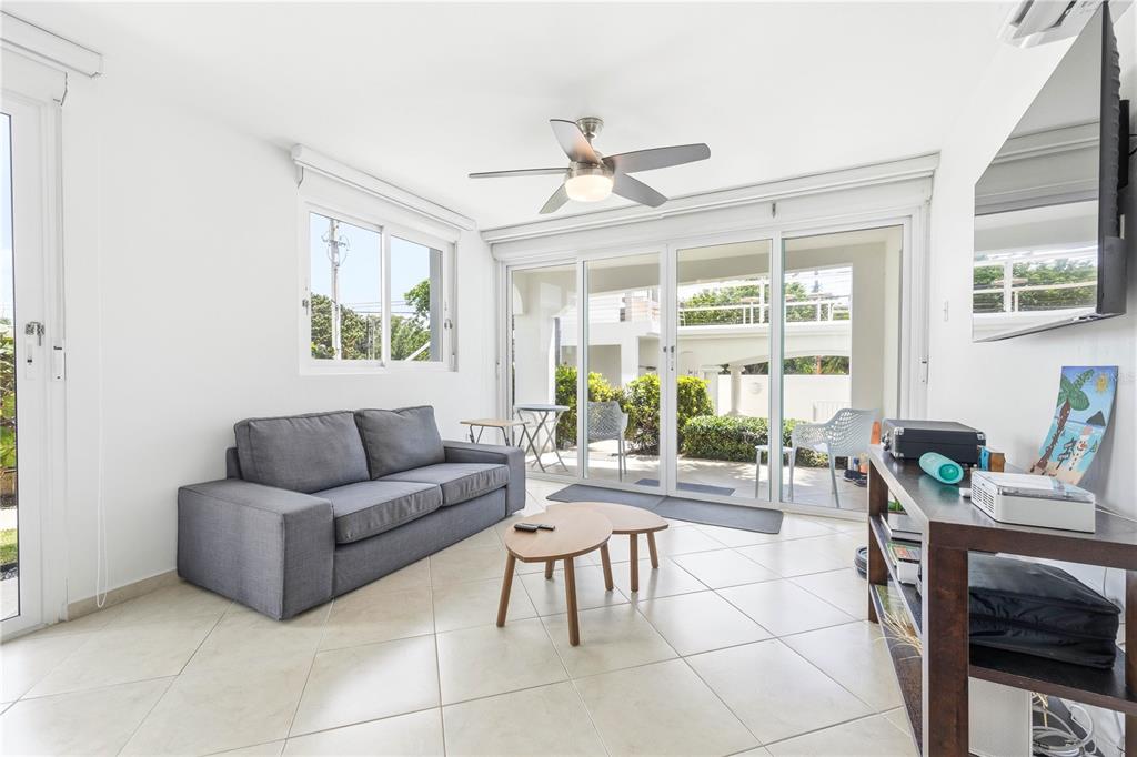 A living room features a grey sofa, two wooden coffee tables, and a sliding glass door — Calle Cambija RINCON OCEAN VIEW UNIT 1D, RINCON, PR
