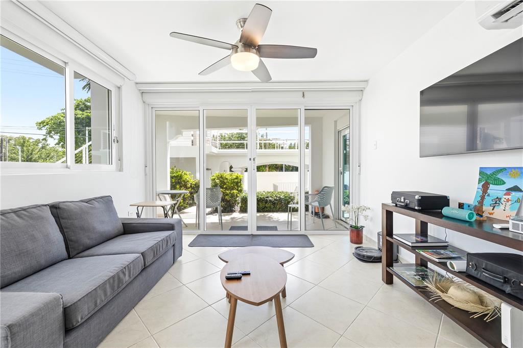 A living room with a gray sofa, coffee table, TV, and sliding glass doors to a patio — Calle Cambija RINCON OCEAN VIEW UNIT 1D, RINCON, PR