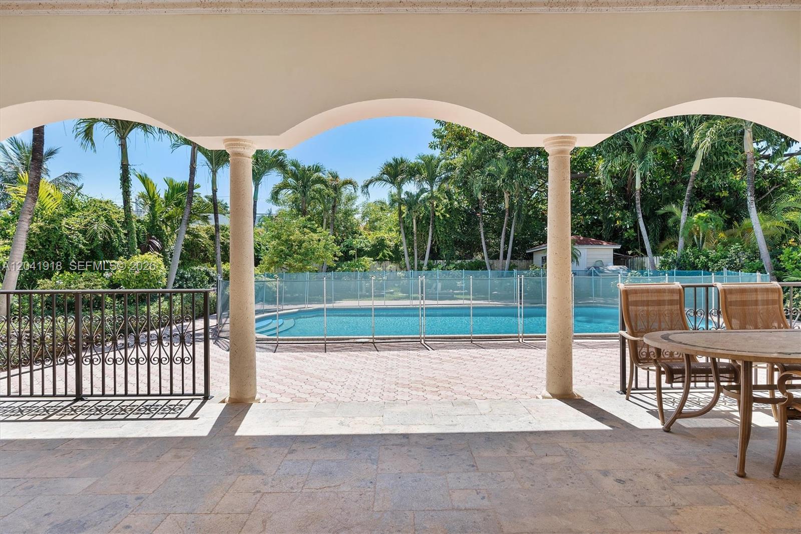 A covered patio overlooks a swimming pool enclosed by a safety fence and palm trees — 3765 Prairie Ave # 3765, Miami Beach FL 33140, MIAMI BEACH, FL