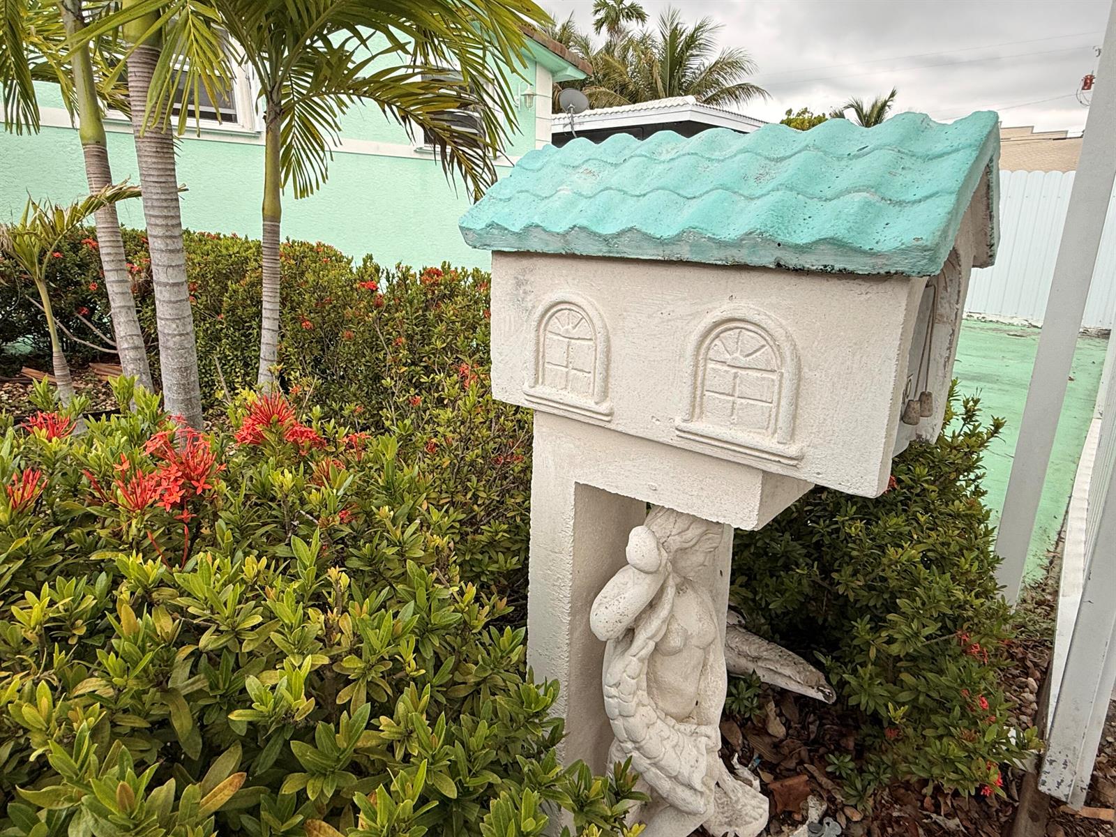 A decorative, house-shaped mailbox with a teal roof stands in front of a green house — 430 NE 75th Street, Miami FL 33138, MIAMI, FL