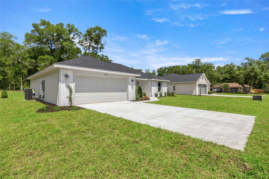 A white single-story house with a two-car garage and a concrete driveway on a lawn — 4038 SW 156TH COURT, OCALA, FL