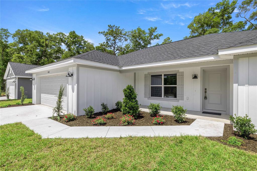 A white single-story house features a gray shingled roof, a garage, and a landscaped yard — 4038 SW 156TH COURT, OCALA, FL