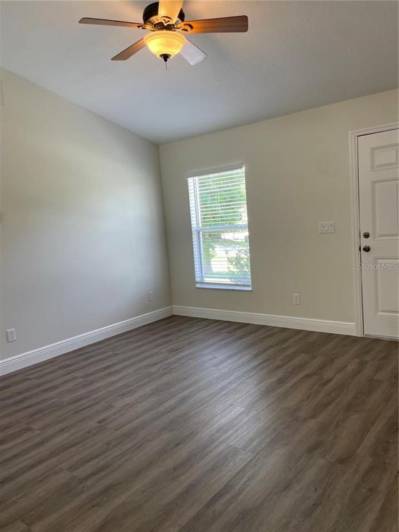 An empty room features light-colored walls, wood-look flooring, a ceiling fan, and a single window — 17542 DORIS STREET, MONTVERDE, FL