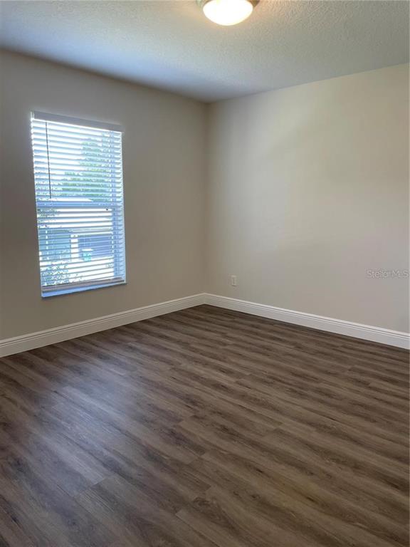 An empty room features light-colored walls, wood-look flooring, and a window with white blinds — 17542 DORIS STREET, MONTVERDE, FL