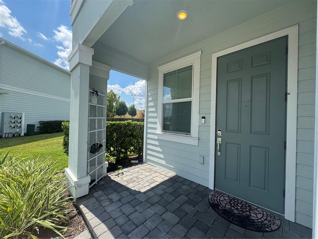 A covered front porch with a paver floor and a light blue door — 4724 TRIBUTE TRAIL, KISSIMMEE, FL