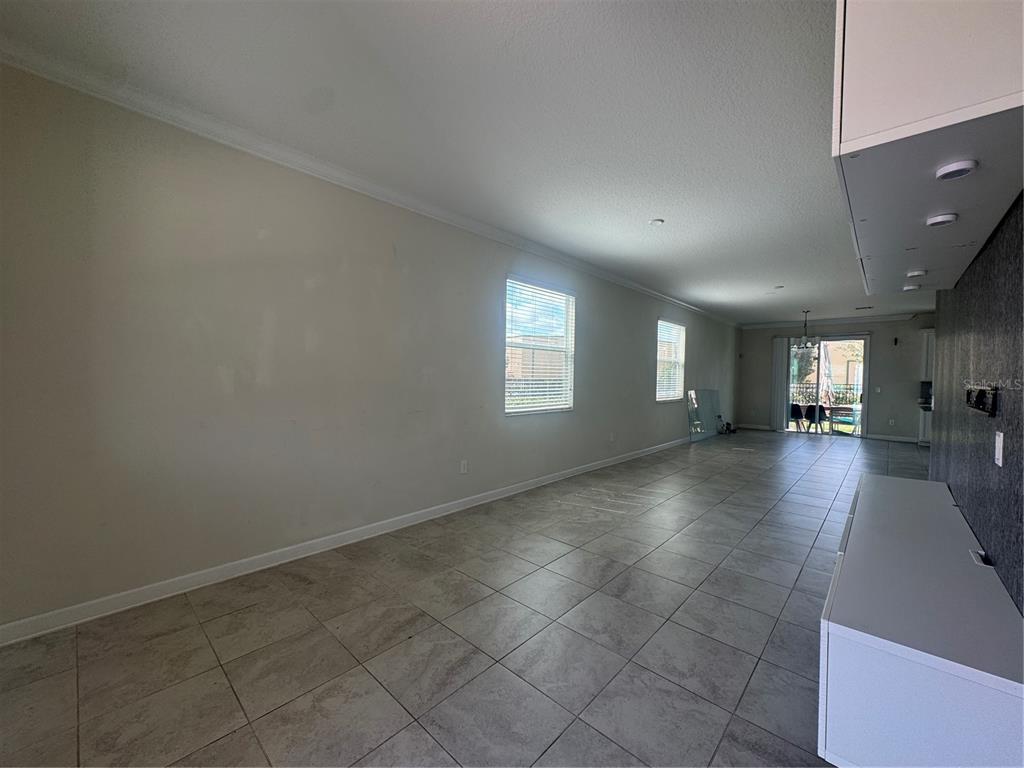 An empty living area features light-colored tile flooring, two windows, and a dark accent wall — 4724 TRIBUTE TRAIL, KISSIMMEE, FL