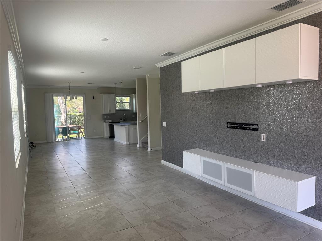 A living room with a gray textured accent wall, white cabinetry, and tile flooring — 4724 TRIBUTE TRAIL, KISSIMMEE, FL