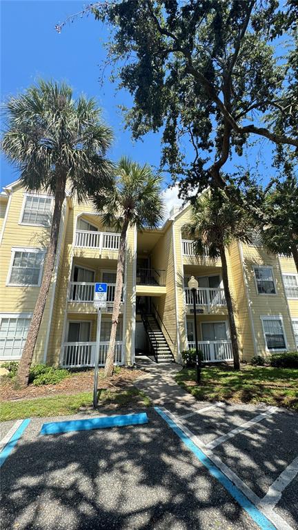 A three-story yellow apartment building features balconies and a handicap parking space in front — 1037 S HIAWASSEE ROAD UNIT 2833, ORLANDO, FL
