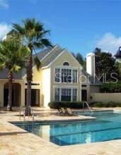 A two-story yellow house with a swimming pool and palm trees in the foreground — 1037 S HIAWASSEE ROAD UNIT 2833, ORLANDO, FL