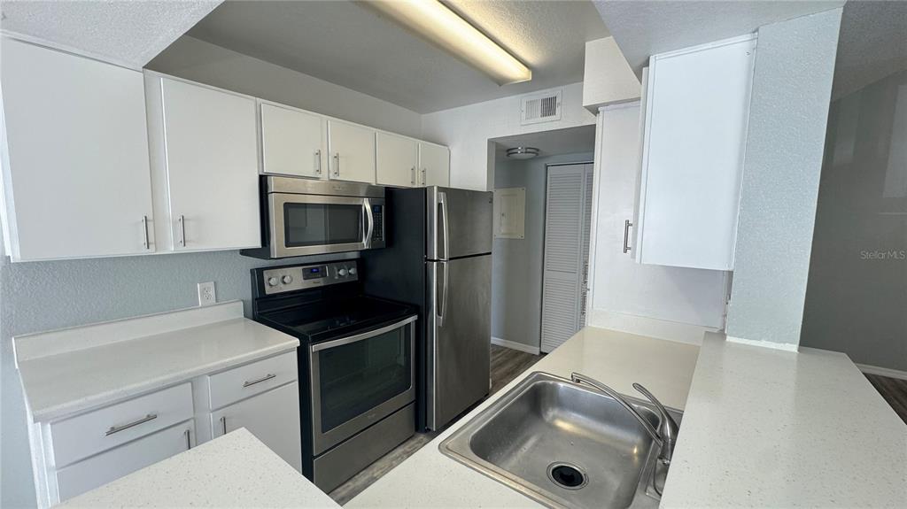A kitchen features white cabinets, stainless steel appliances, and a stainless steel sink — 1037 S HIAWASSEE ROAD UNIT 2833, ORLANDO, FL